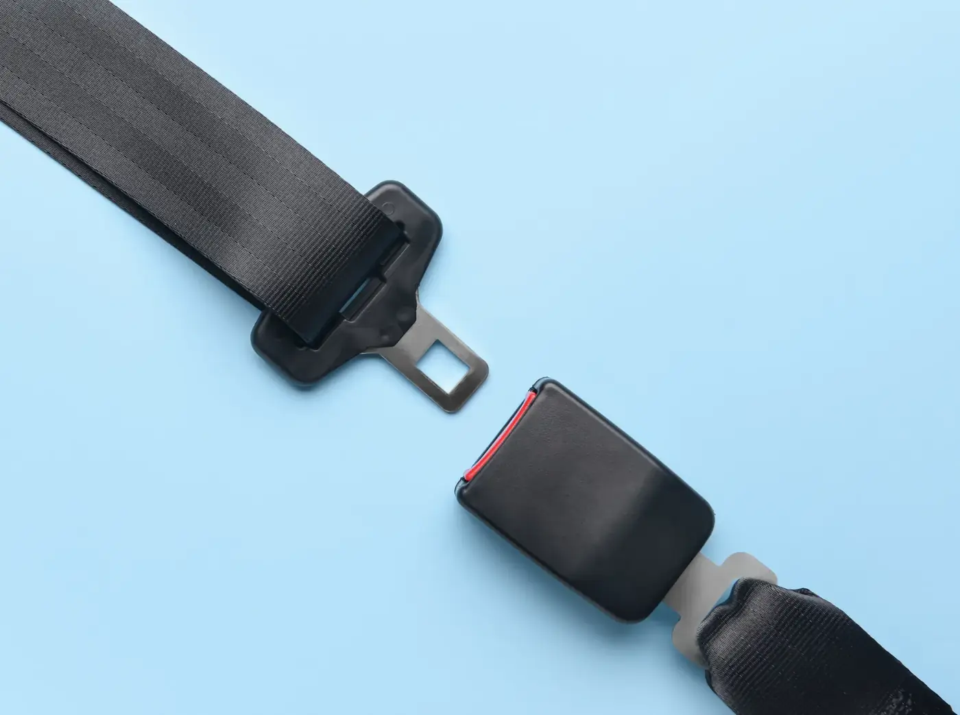 Complete automotive seat belt assembly laid flat with webbing, latch plate and buckle housing visible