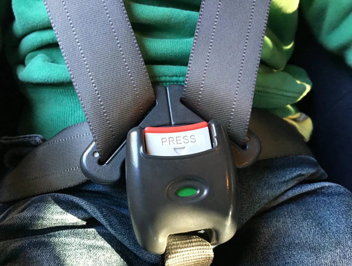 Harness buckle fastened across an occupant in a rear vehicle seat