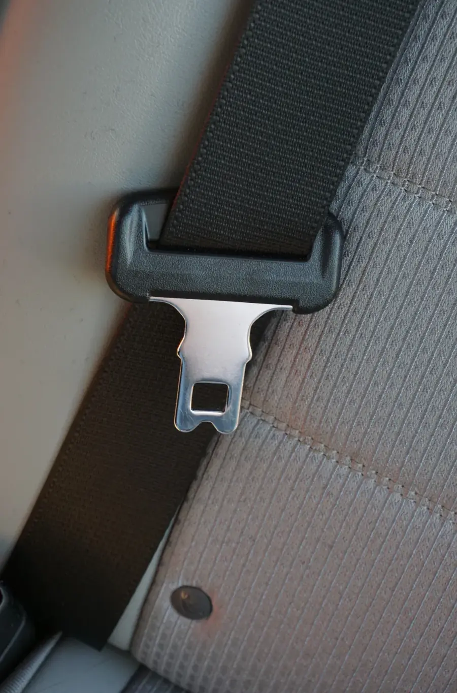 Seat belt webbing passing through a moulded guide with the metal tongue plate suspended below it